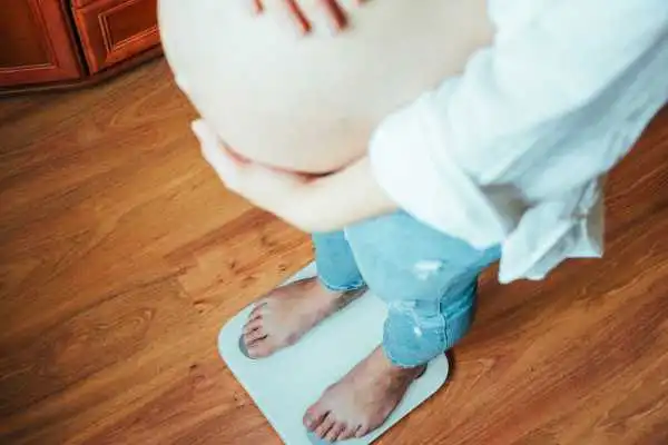 Image of woman weighing herself and experiencing weight gain through pregnancy Cardonald